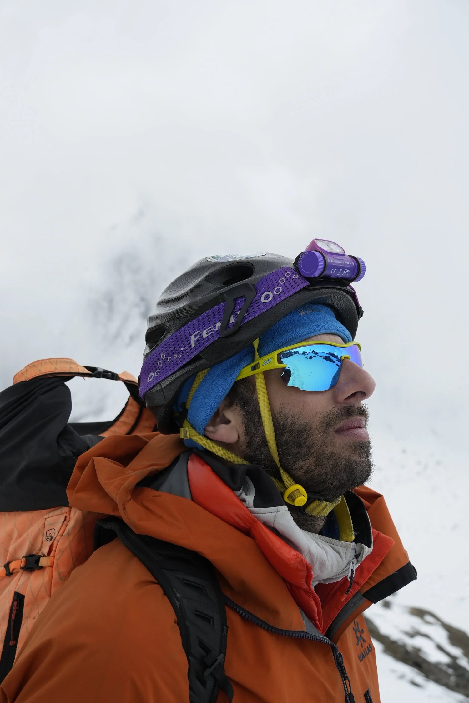 Bergsteiger mit Fenix Stirnlampe und orangefarbener Ausrüstung bei nebligem Bergwetter in Österreich