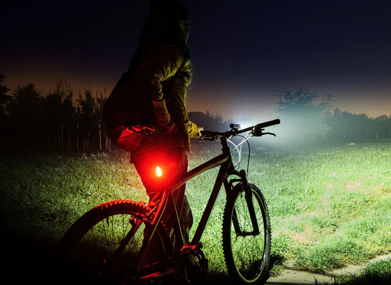 Mann mit rotem Helm und Fahrrad in Regen bei Nacht mit heller Fenix Fahrradbeleuchtung im Wald
